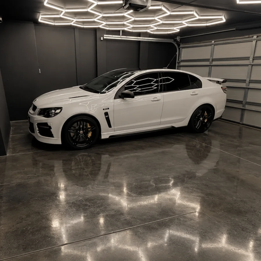 Polished concrete garage floor under hexagon lighting, reflecting the lights beside a white car